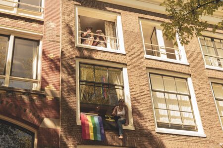 Amsterdam, Netherlands - August 3, 2013: A vintage color tone picture  of Amsterdam gay parade in a canal on a sunny day with people greeting prideのeditorial素材