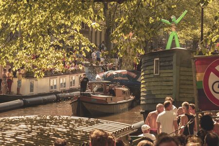 Amsterdam, Netherlands - August 3, 2013: A vintage color tone picture  of Amsterdam gay parade in a canal on a sunny day with people having fun dancing on a boatのeditorial素材