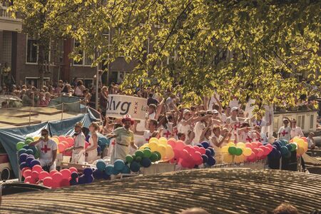 Amsterdam, Netherlands - August 3, 2013: A vintage color tone picture  of Amsterdam gay parade in a canal on a sunny day with people having fun dancing on a boatのeditorial素材
