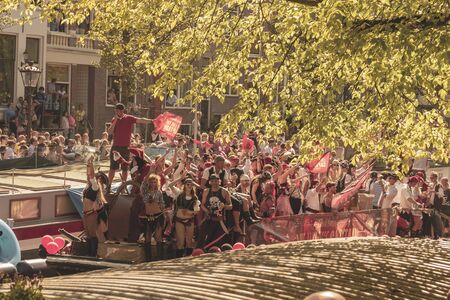 Amsterdam, Netherlands - August 3, 2013: A vintage color tone picture  of Amsterdam gay parade in a canal on a sunny day with people having fun dancing on a boatのeditorial素材