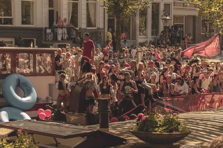 Amsterdam, Netherlands - August 3, 2013: A vintage color tone picture  of Amsterdam gay parade in a canal on a sunny day with people having fun dancing on a boatのeditorial素材
