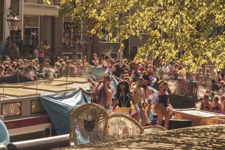 Amsterdam, Netherlands - August 3, 2013: A vintage color tone picture  of Amsterdam gay parade in a canal on a sunny day with people having fun dancing on a boatのeditorial素材