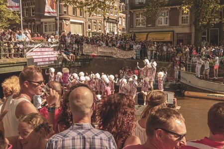 Amsterdam, Netherlands - August 3, 2013: A vintage color tone picture  of Amsterdam gay parade in a canal on a sunny day with people having fun dancing on a boatのeditorial素材