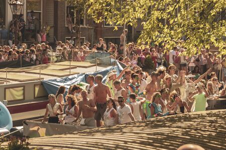 Amsterdam, Netherlands - August 3, 2013: A vintage color tone picture  of Amsterdam gay parade in a canal on a sunny day with people having fun dancing on a boatのeditorial素材