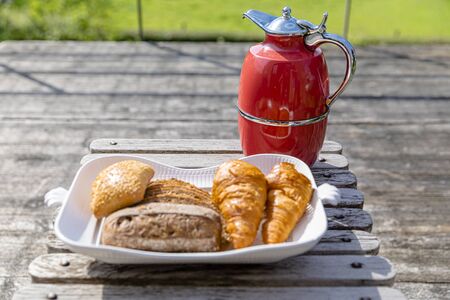fresh Breakfast: a pot of coffee, a plate of croissants. Stand on the table on the summervillage verandaの写真素材