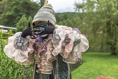 A man standing in mask and masquerade costume agains the park backgroundの写真素材