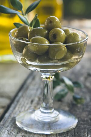 glass cup full of olives with green backgroundの写真素材