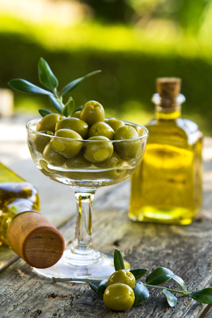 glass cup full of olives with green backgroundの写真素材
