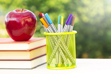 back to school, books, apple and colored marker pens on green backgroundの写真素材