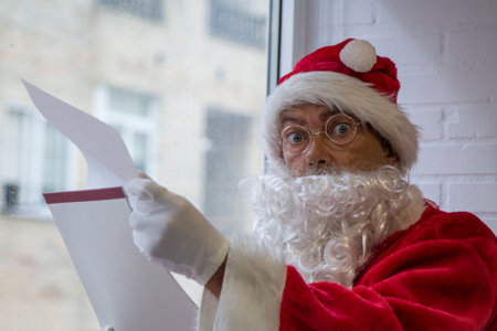 santa claus with her notebook in her hand pensive and focused on the plan of the wish list and gifts to decide what to chooseの写真素材