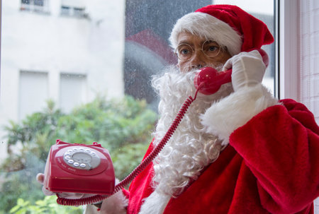 santa claus calling with a red vintage cord phoneの写真素材