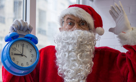 santa claus with alarm clock at christmas and surprise expressionの写真素材