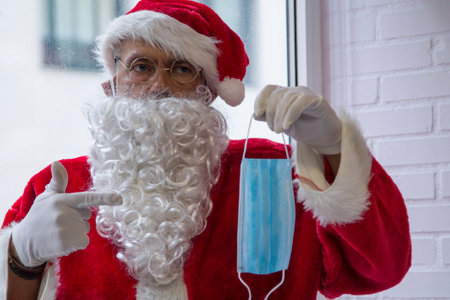 santa claus pointing at the disposable mask at christmasの写真素材