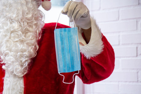 santa claus holding disposable medical mask in hand at christmasの写真素材