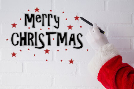 Santa Claus writing Christmas greeting with the pen on the white brick wallの写真素材