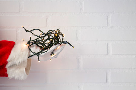 Santa Claus hand holding christmas lights on backgroundの写真素材