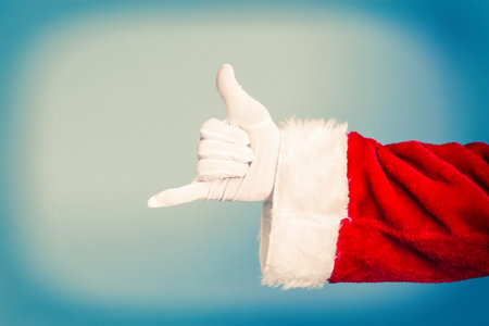 santa claus makes call me gesture, raises arm to ear, pretends speaking on phoneの写真素材