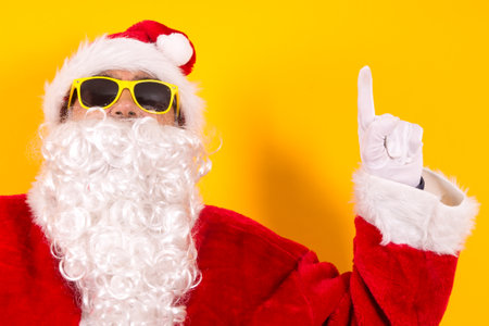 santa claus pointing with finger on yellow backgroundの写真素材
