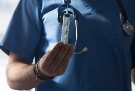 doctor with stethoscope and syringe, medicine and infections conceptの写真素材