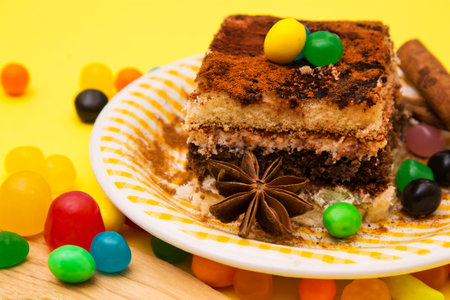 Tiramisu dish with cinnamon and candies on yellow backgroundの写真素材