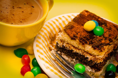 Tiramisu dish with cinnamon and candies on yellow backgroundの写真素材