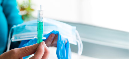 hand with syringe and mask with disposable medical gloves, concept of vaccine for covid-19の写真素材