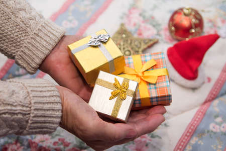 Woman holding Christmas gift boxes with Christmas decorations in the background, Christmas greeting