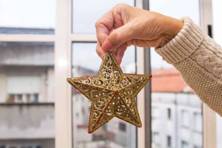 Christmas star decor in women hand. Christmas greeting card. Woman's hands hold christmas or new year decorated gift.の写真素材