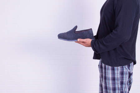 man in pajamas holding house slippersの写真素材