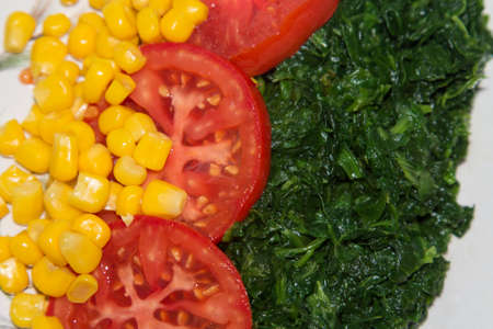 plate of tomato, corn and spinach salad close-up view, diet and health conceptの写真素材