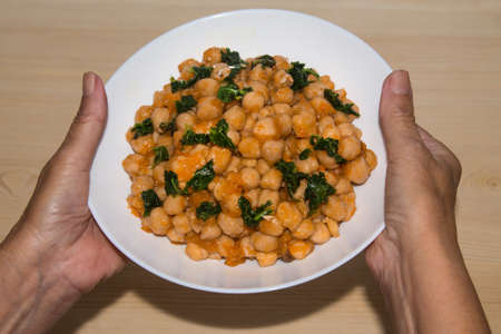 holding plate of chickpeas and spinach, diet and food conceptの写真素材