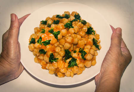 woman hands holding bowl of chickpeas with spinachの写真素材