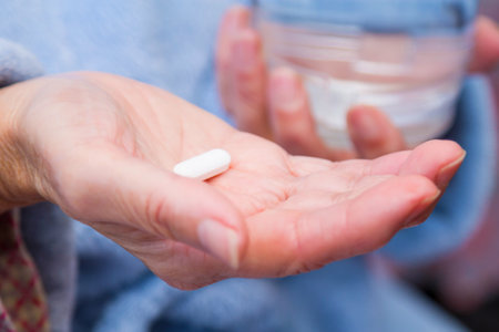 Woman with pills or capsules on hand and a glass of waterの写真素材