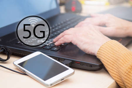 woman using laptop and cellphone with 5G icon