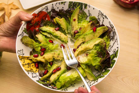 eating bowl of guacamole, lettuce and pomegranate. healthy and dietary foodの写真素材