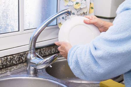 woman putting detergent in the scourer, to wash the dishesの写真素材