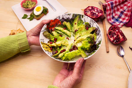 holding bowl of guacamole, lettuce and pomegranate