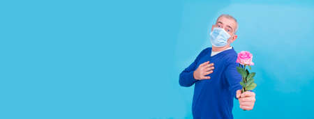 Valentine's Day during the  pandemic concept. attractive man with surgical mask and pink flower. ...