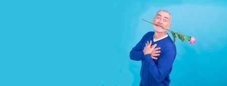 attractive and funny senior man with rose in his mouth to celebrate valentines dayの写真素材