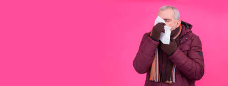 cold senior man blowing his nose with handkerchiefの写真素材