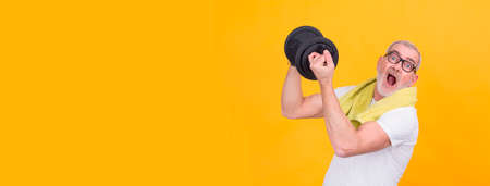 senior man with towel straining with dumbbellsの写真素材