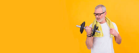 senior man with towel straining with dumbbellsの写真素材