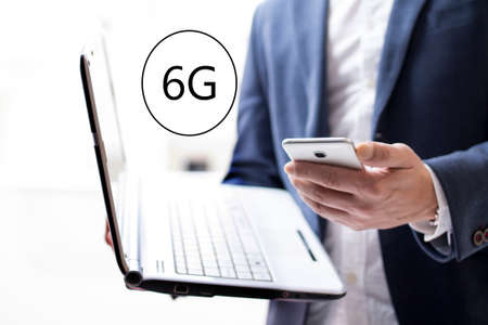 6G concept with businessman with his laptop and cellphoneの写真素材
