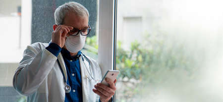 doctor with mask using mobile phoneの写真素材
