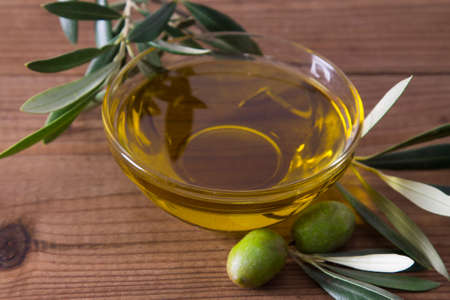 glass vessel with extra virgin olive oil and olives with branchの写真素材