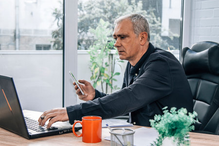 businessman in office with phone and using computerの写真素材