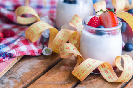 natural yogurt with strawberries and measuring tape, concept of diet and healthの写真素材