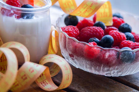 greek yogurt with strawberries and blueberries and measuring tape, diet and health conceptの写真素材