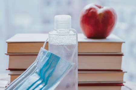 books, apple and medical mask. back to school concept in the new normal