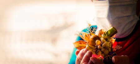 senior woman with disposable surgical mask placing christmas decorations